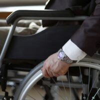 Disability businessman with wheelchair against business office